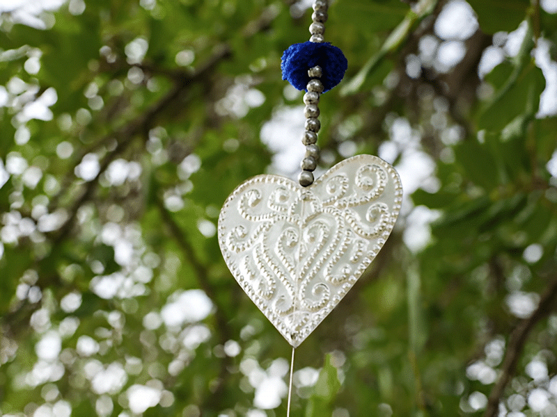 Silver heart shaped ornament hanging from a tree branch to celebrate Moon Ceremony.
